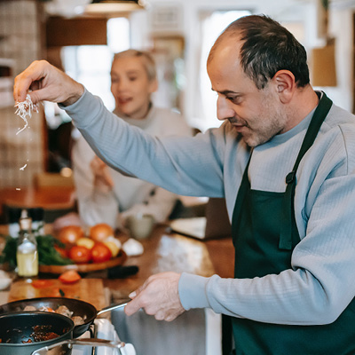 Ein Mann steht in der Küche und kocht mit der Familie zusammen